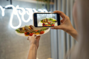 A girl is taking a picture of food with her phone in a restaurant