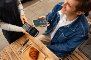Customer making a contactless payment with a smartphone at a café with PAYSPOS terminal